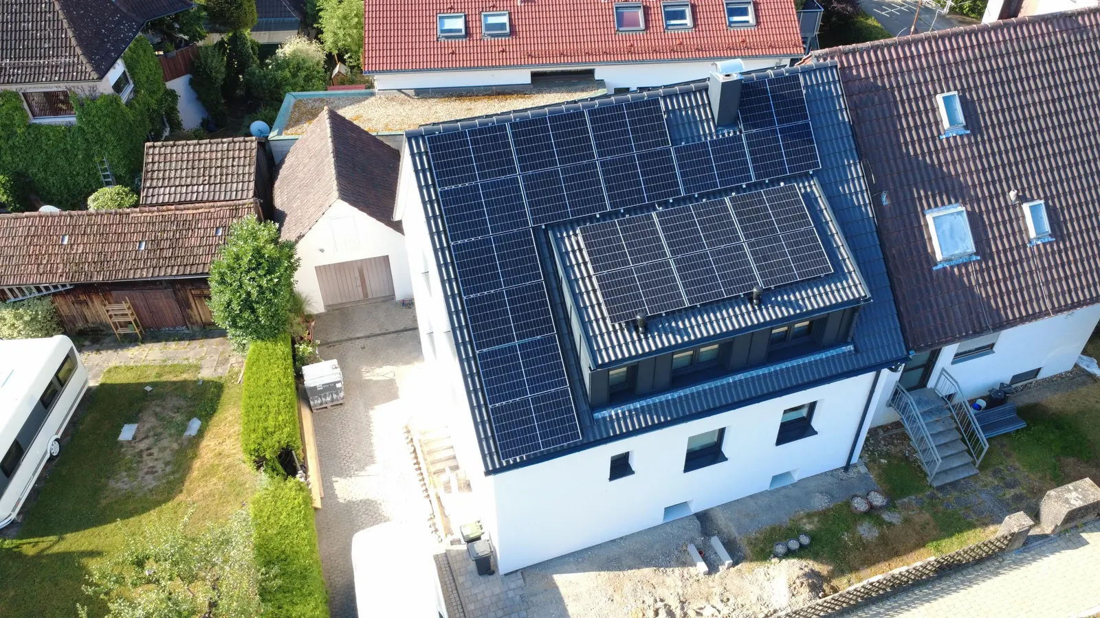 Fully covered dark pitched roof with dormer and photovoltaics