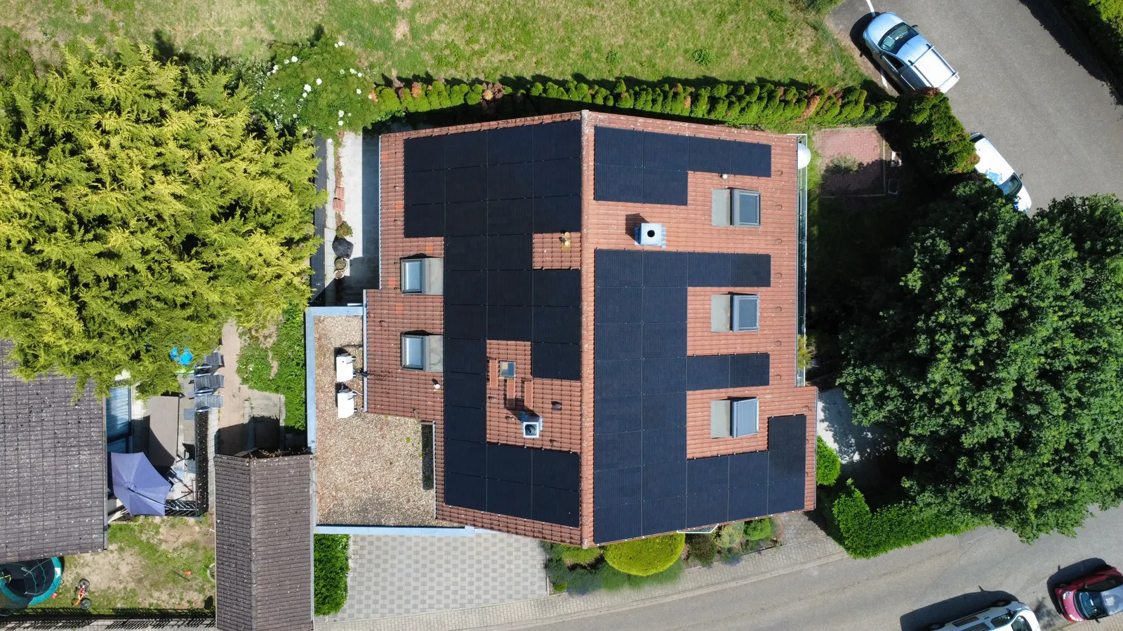 Photovoltaic system fitted around roof windows on red tiles